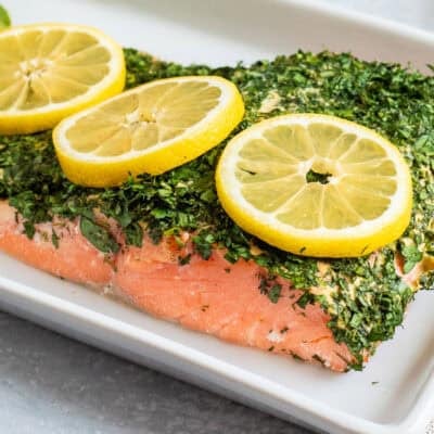 Baked Herbed Salmon on a platter with slices of lemon garnish.