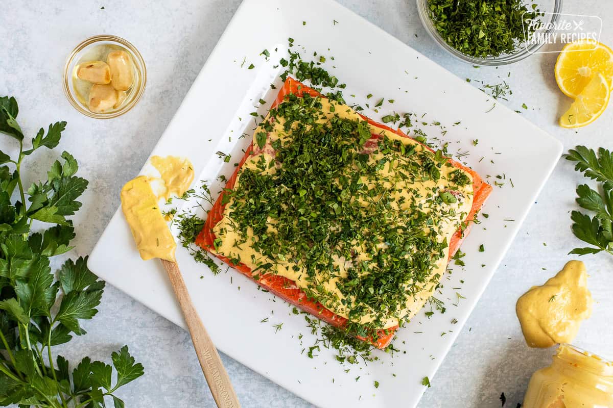 Salmon fillet with Dijon mustard spread on top and fresh chopped herbs.