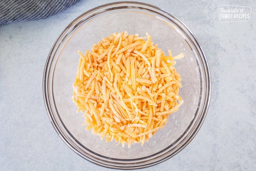 Glass bowl with shredded cheddar cheese tossed with cornstarch.