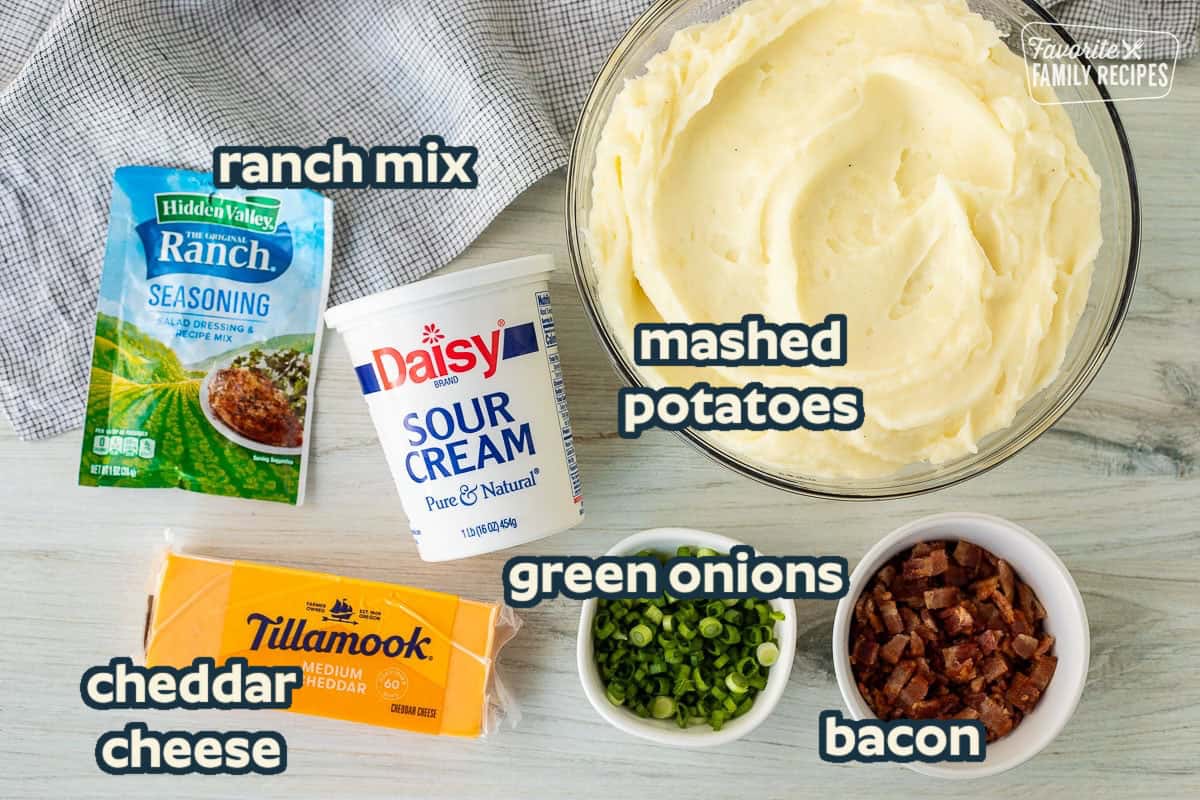 Ingredients for Loaded Mashed Potatoes including mashed potatoes, sour cream, ranch dressing seasoning, cheddar cheese, green onions and bacon.
