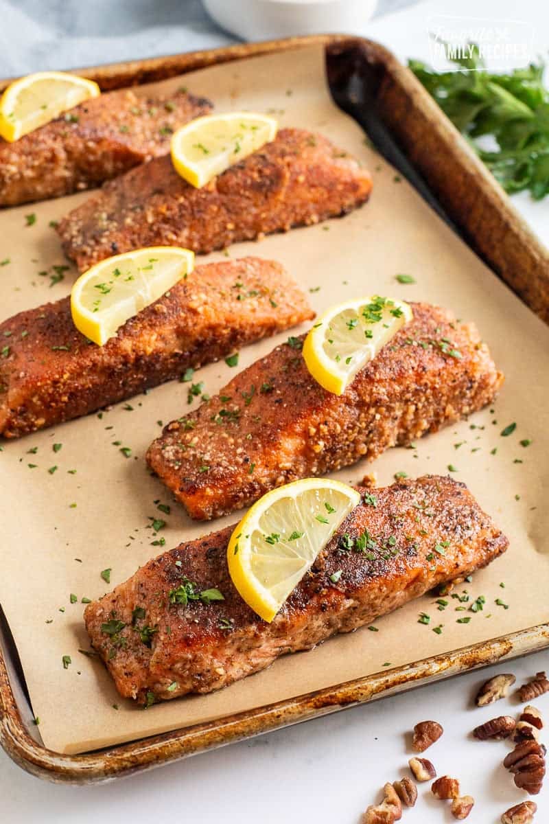 Sheet pan with five pieces of Pecan Salmon and garnished with lemon slices.