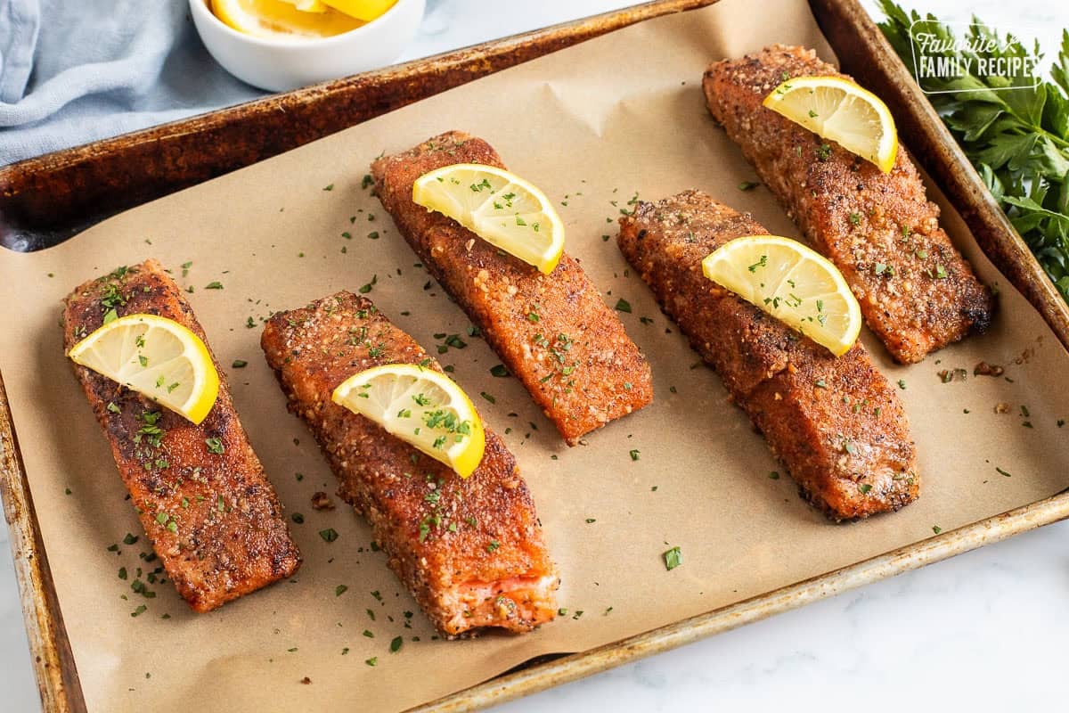 Sheet pan with five pieces of Pecan Salmon and garnished with lemon slices.