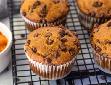 Baked pumpkin chocolate chip muffins on a cooling rack.