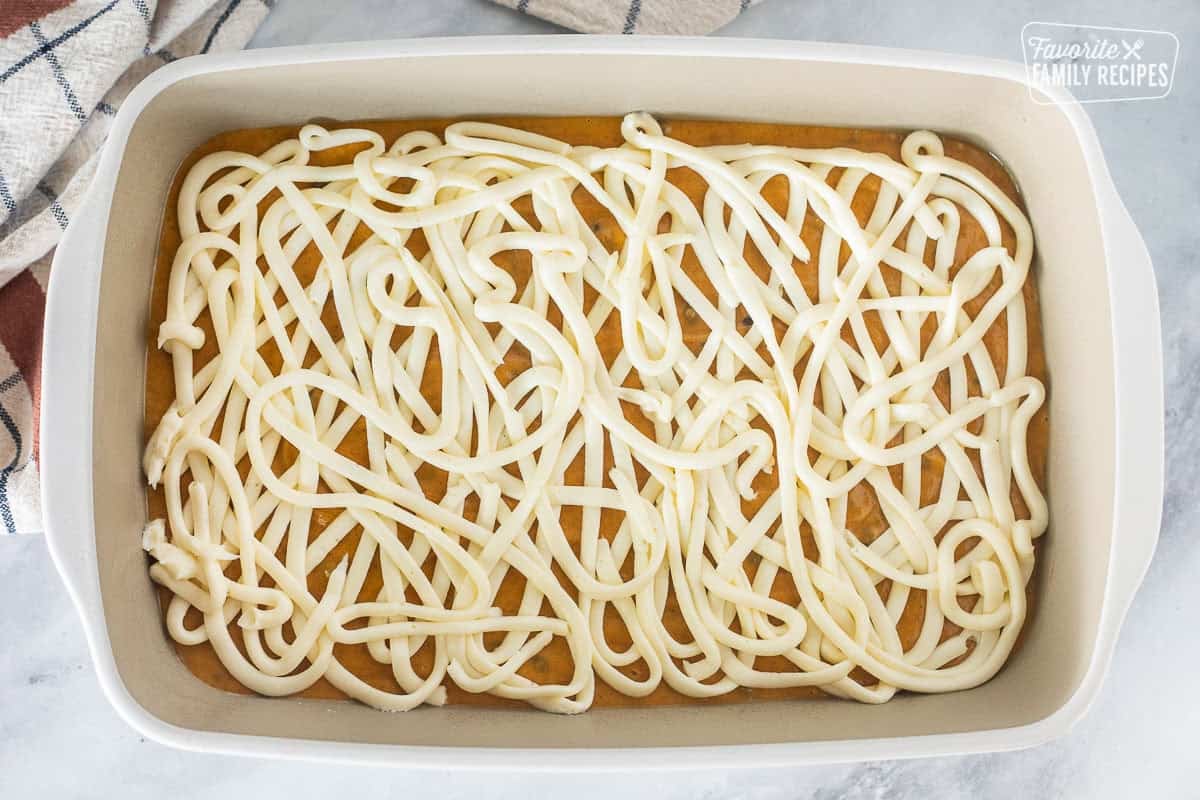 Baking dish with cream cheese swirled all over top of pumpkin coffee cake batter.