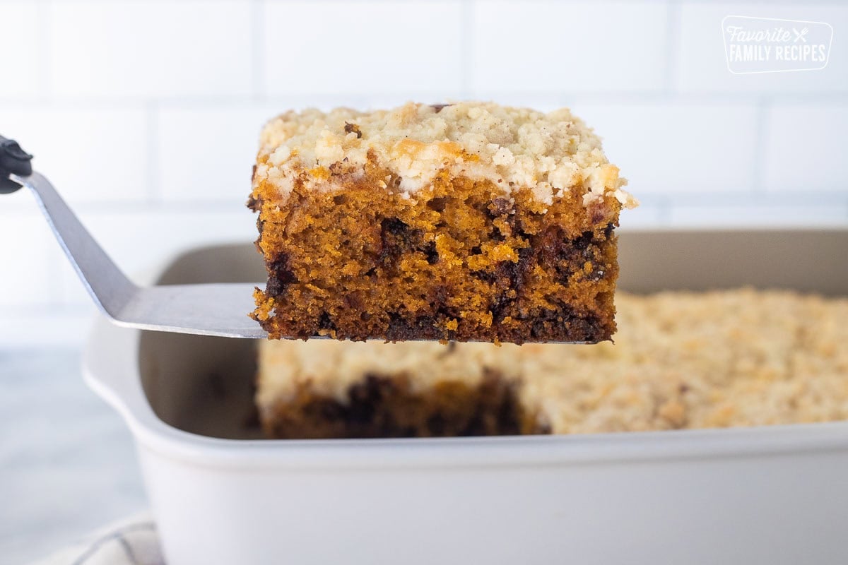 Slice of pumpkin coffee cake on a spatula over baking dish.