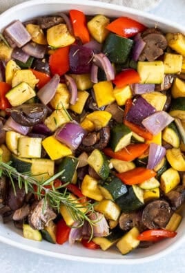Dish of roasted vegetables including zucchini, yellow squash, red onion, red bell pepper and mushroom.