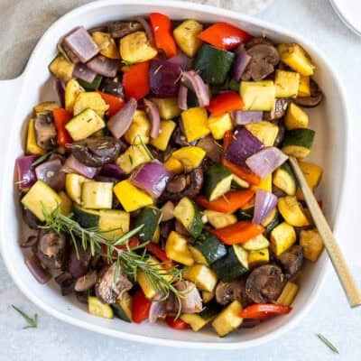 Dish of roasted vegetables including zucchini, yellow squash, red onion, red bell pepper and mushroom.
