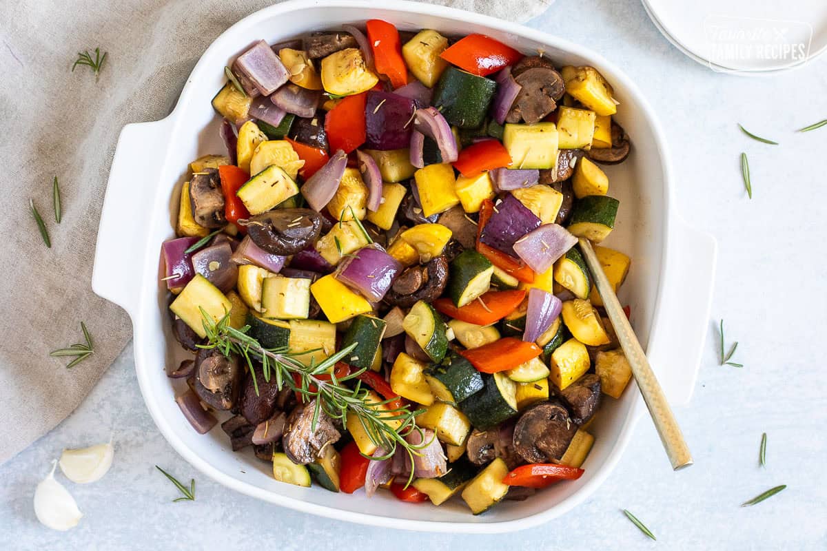 Dish of roasted vegetables including zucchini, yellow squash, red onion, red bell pepper and mushroom.