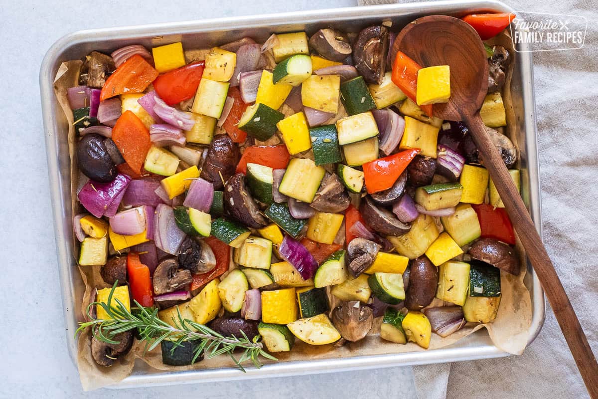 Sheet pan of oven roasted vegetables including zucchini, yellow squash, red onion, red bell pepper and mushroom.