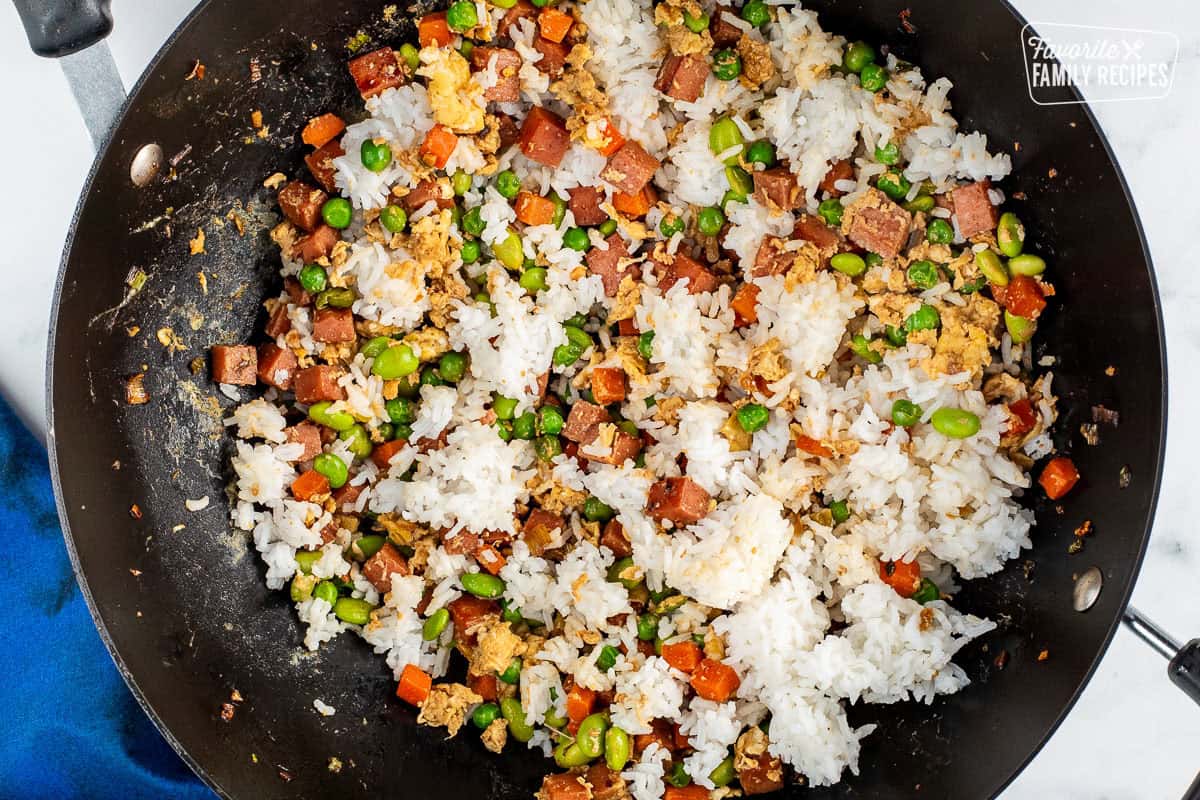 Wok with cold white rice added to spam vegetable mixture.