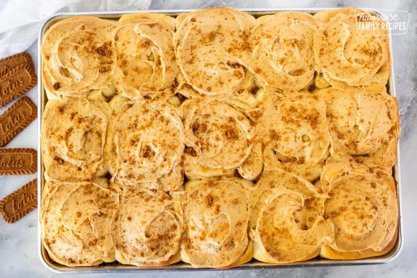 Fifteen Biscoff Cinnamon Rolls frosted with Biscoff frosting and cookie crumbles on top.