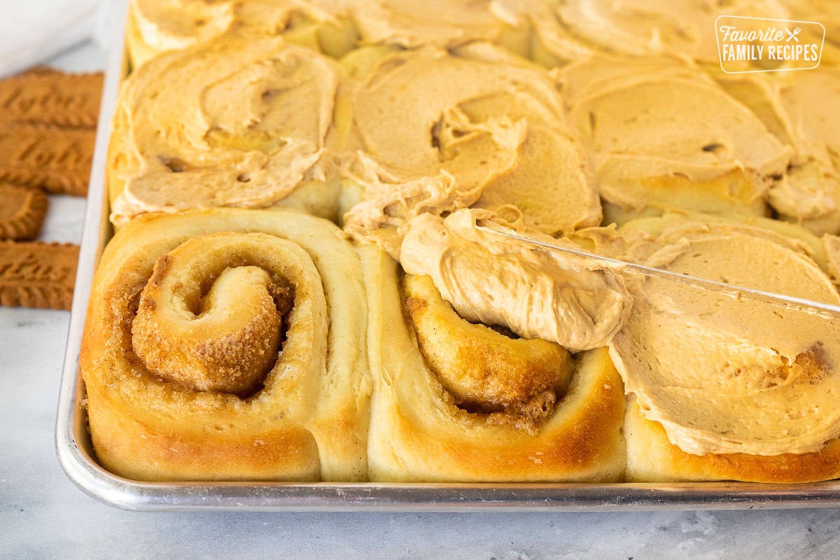 Spreading Biscoff frosting on top of baked Biscoff Cinnamon Rolls.