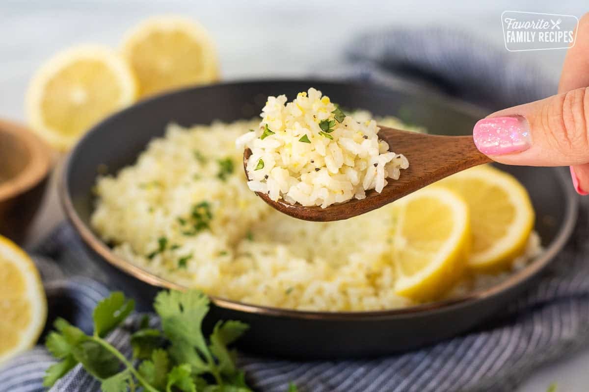 Spoon of lemon rice over a bowl garnished with cilantro.