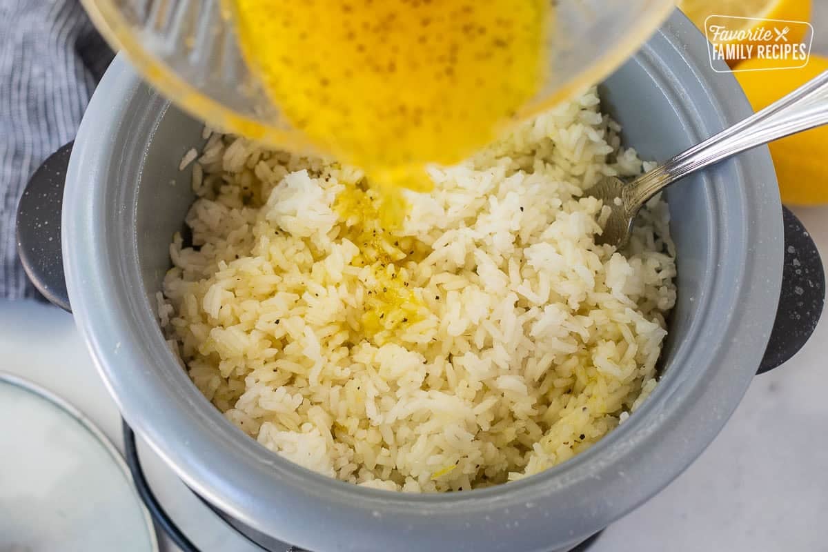 Pouring lemon mixture in fluffed up rice.