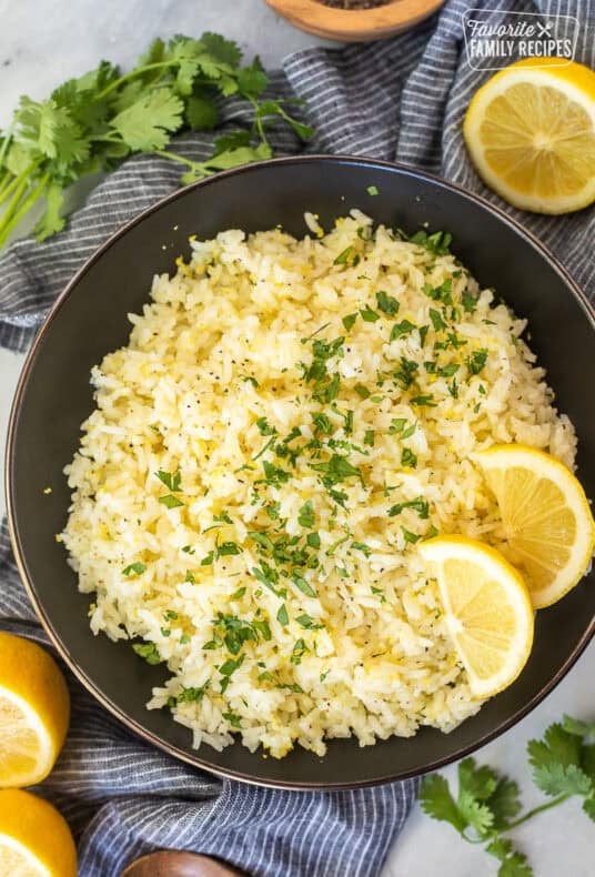 Bowl of easy lemon rice garnished with cilantro and fresh lemon wedges.