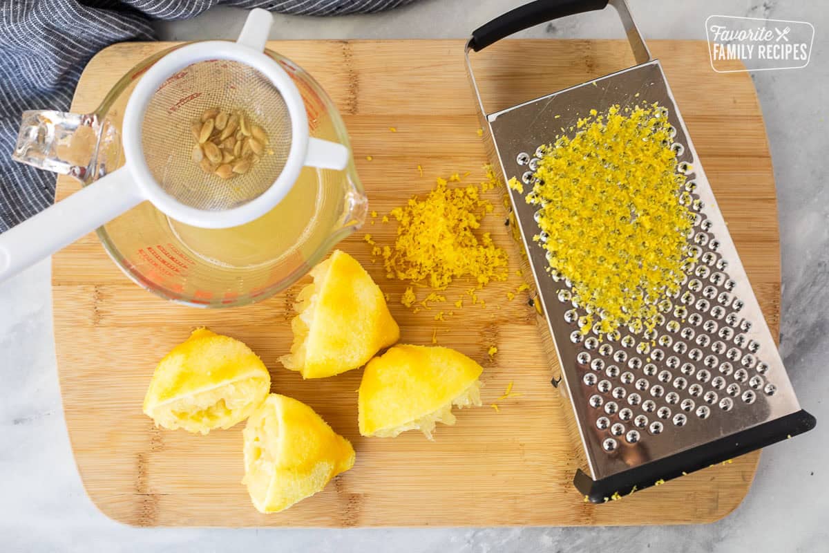 Cutting board with lemon zest and juiced in a glass jar.