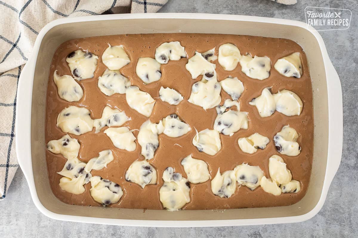 Baking dish with German chocolate cake batter and Cream cheese chocolate chip scoop.