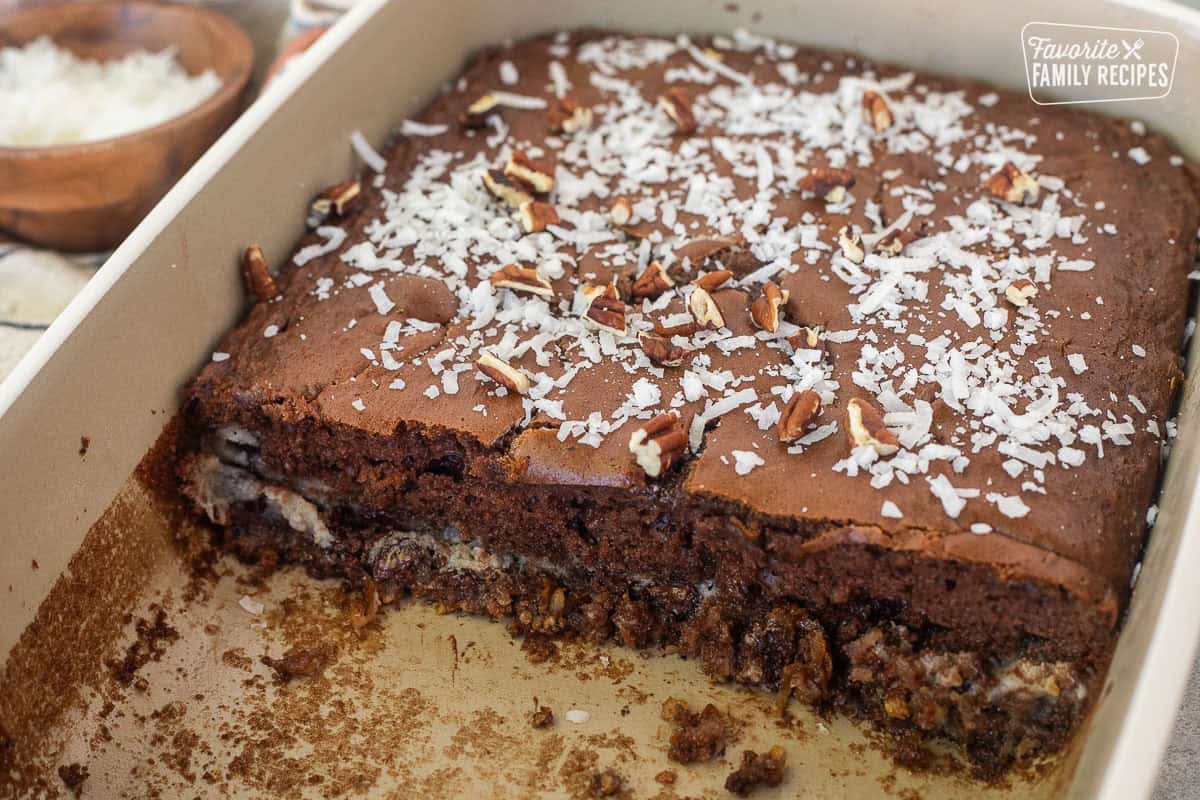 Baking dish with cut German Chocolate cake with coconut flakes and pecan pieces on top.