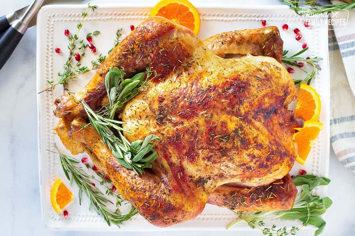 Follow these basic steps for how to cook a turkey and you will enjoy a tender, juicy turkey without fail. Thanksgiving turkey on a platter with sage, thyme and orange slices.