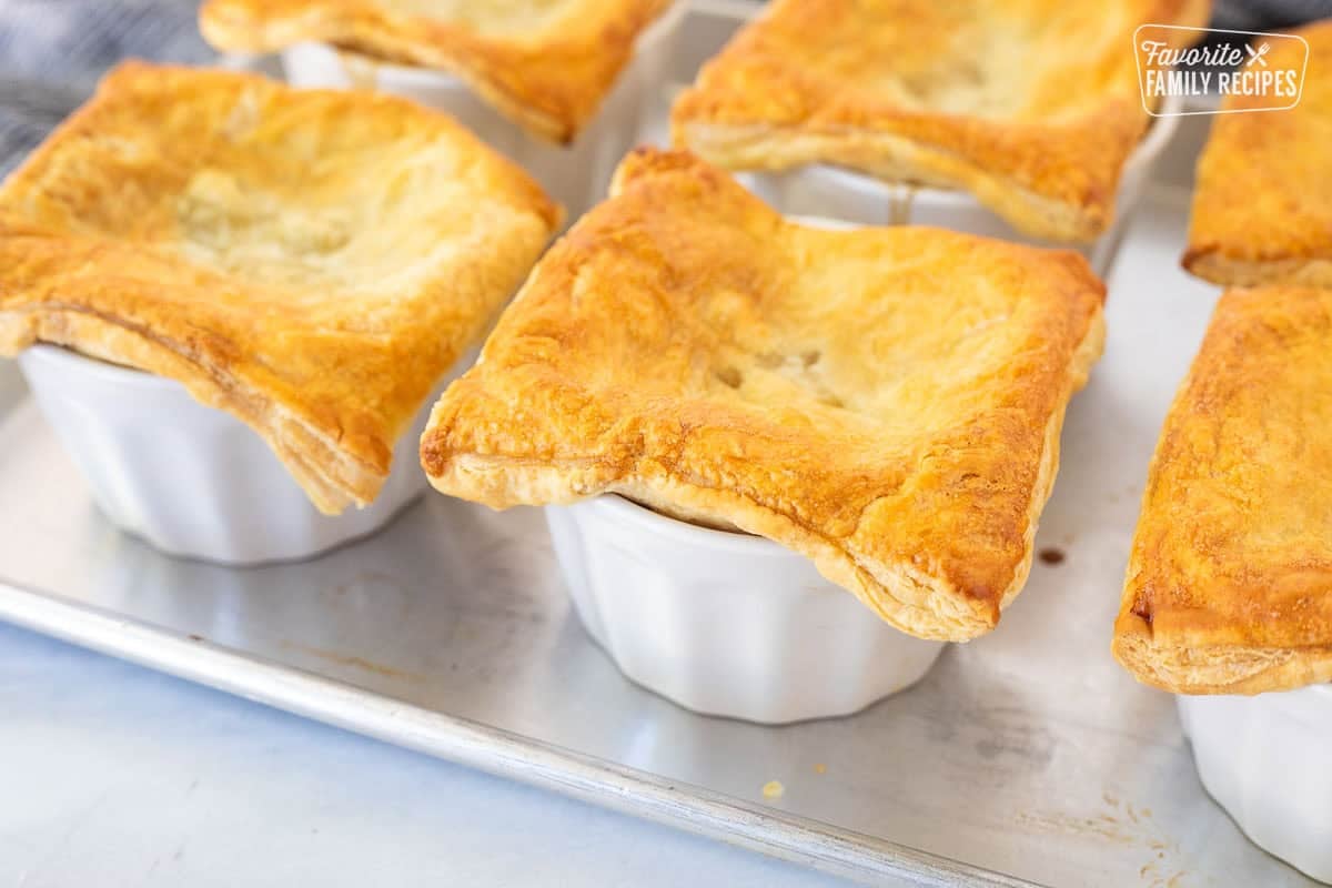 Baked instant pot beef pot pie in ramekins on a sheet pan.
