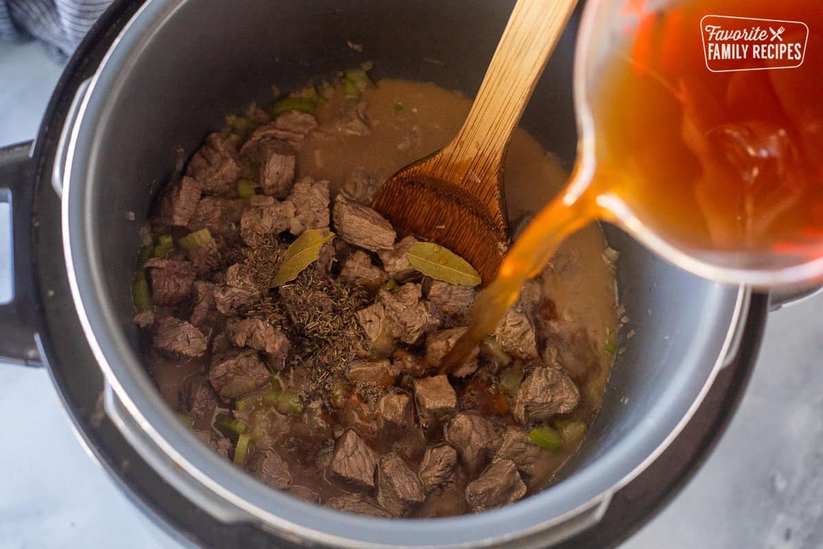 Pouring beef broth inside instant pot with ground beef, thyme and bay leaves.