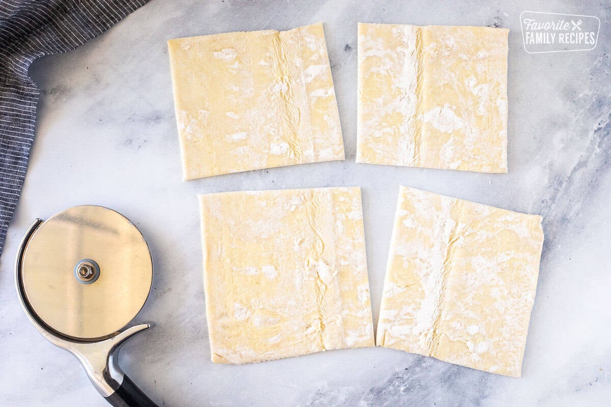 Puff pastry sheet cut into four squares with a pizza cutter.