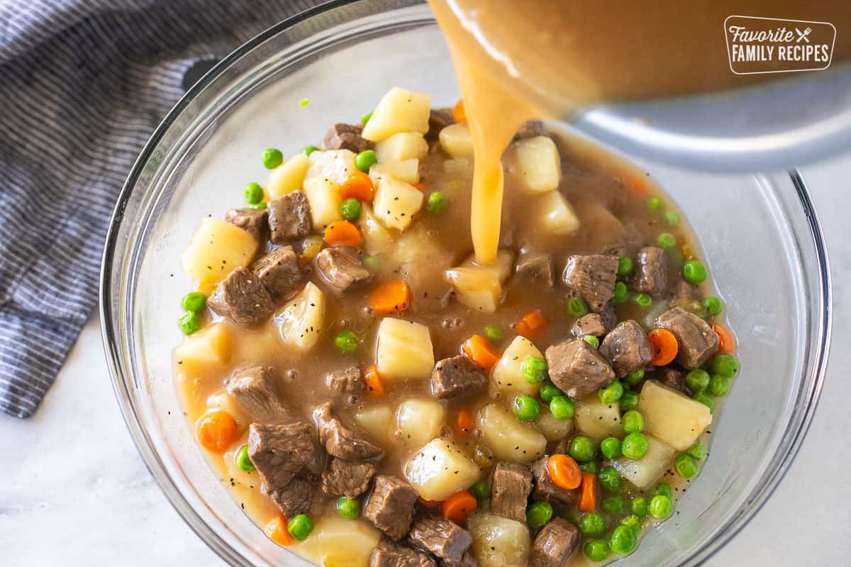 Pouring beef gravy on top of cooked instant pot vegetables in a bowl.