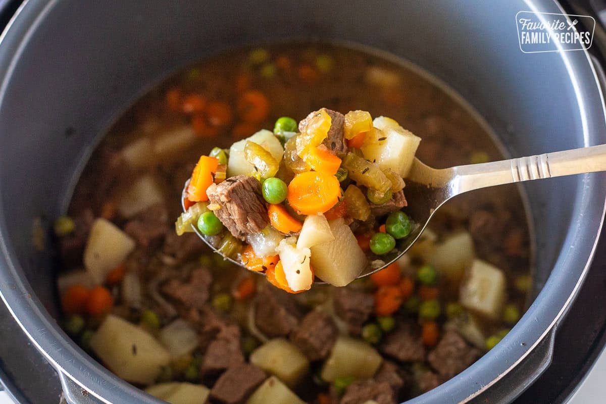 Removing beef and vegetables with a slotted spoon from the instant pot broth.