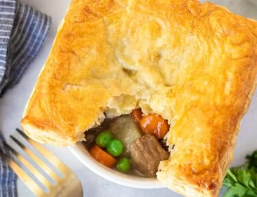 Instant Pot Beef Pot Pie in a ramekin with beef, carrots, potatoes, peas and gravy.