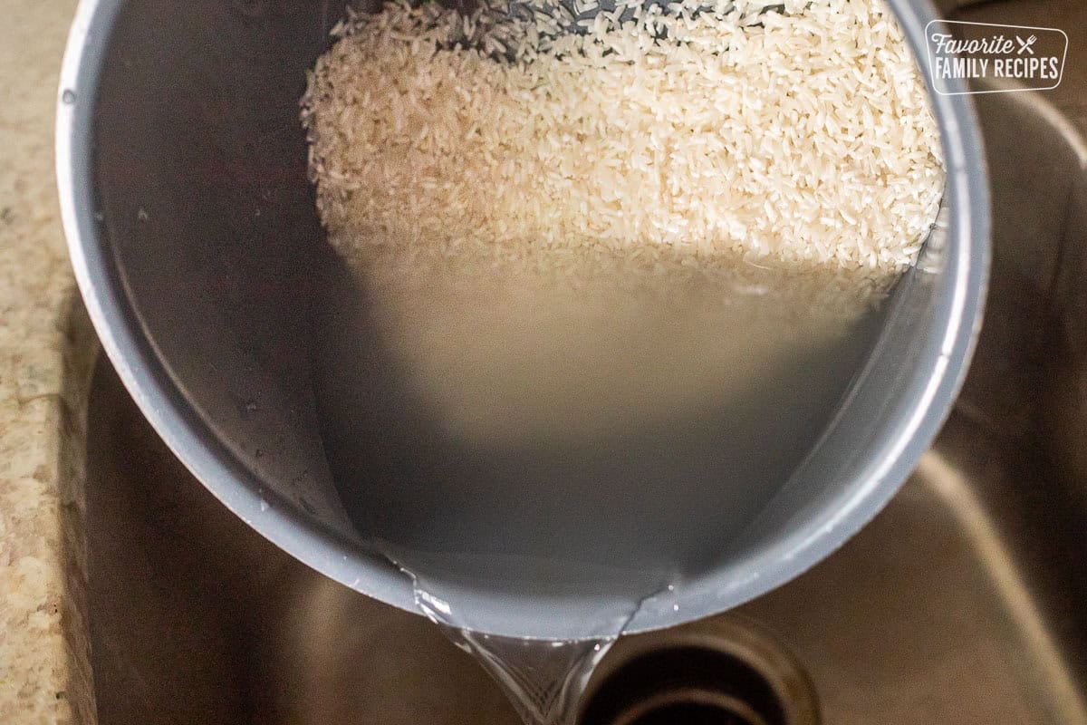 Pouring clear water out of rinsed rice in an instant pot.
