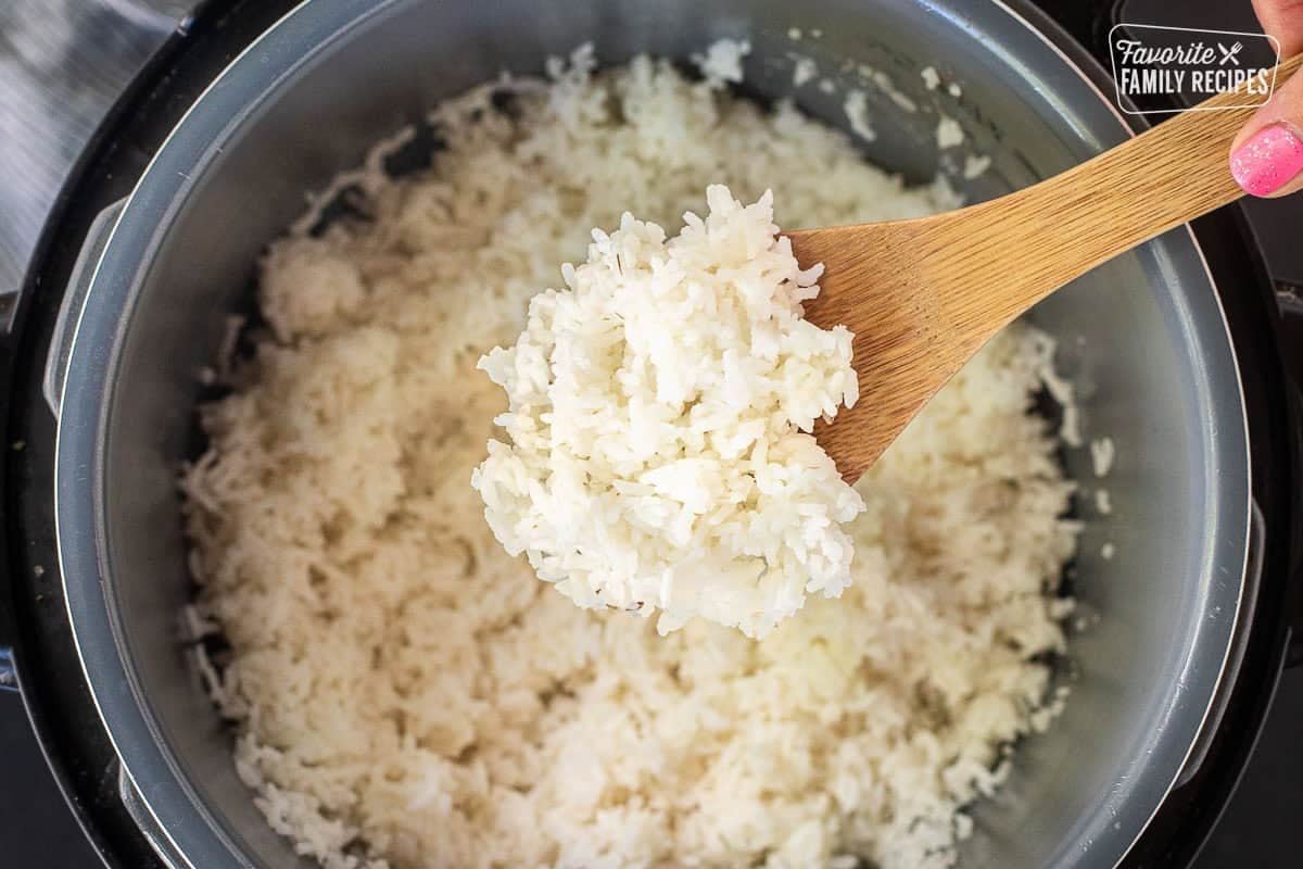 Instant pot rice in a wooden spoon over the instant pot of rice.