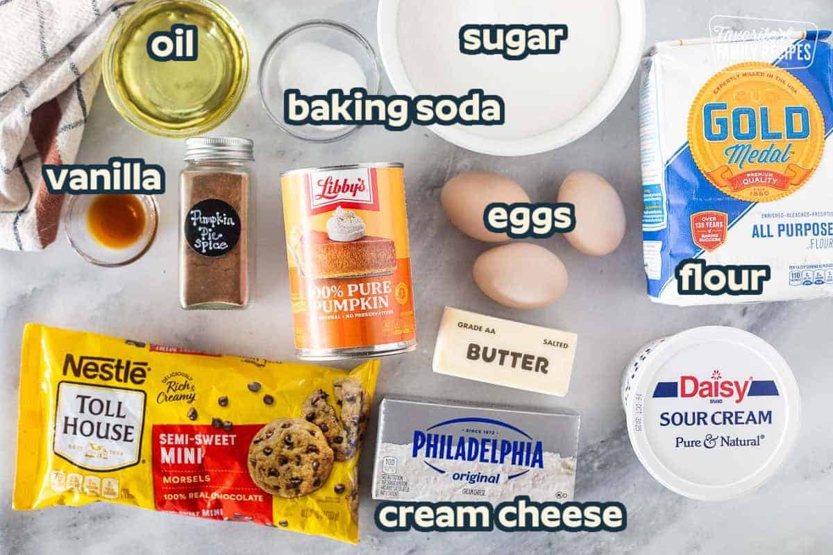 Ingredients for a pumpkin coffee cake recipe on a kitchen counter: pumpkin, flour, eggs, baking soda, sugar, oil, pumpkin pie spice, etc.