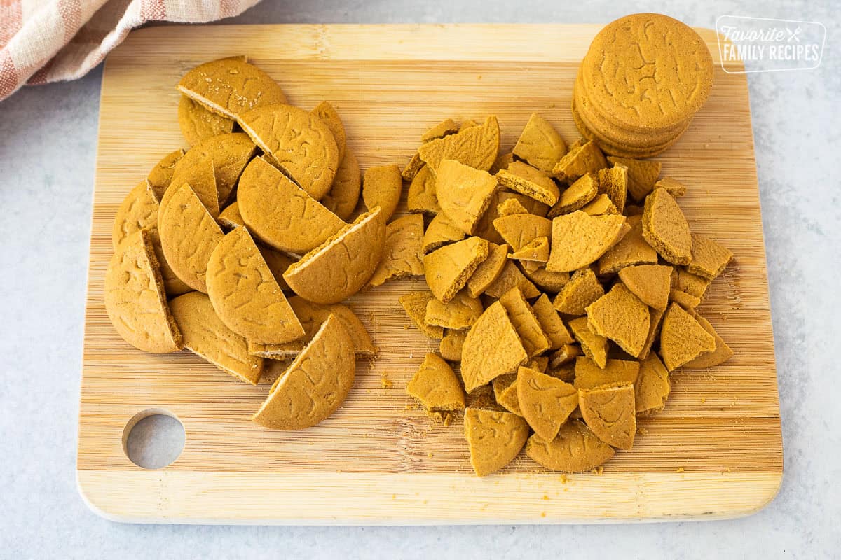 Halved and chopped ginger snap cookies on a cutting board.