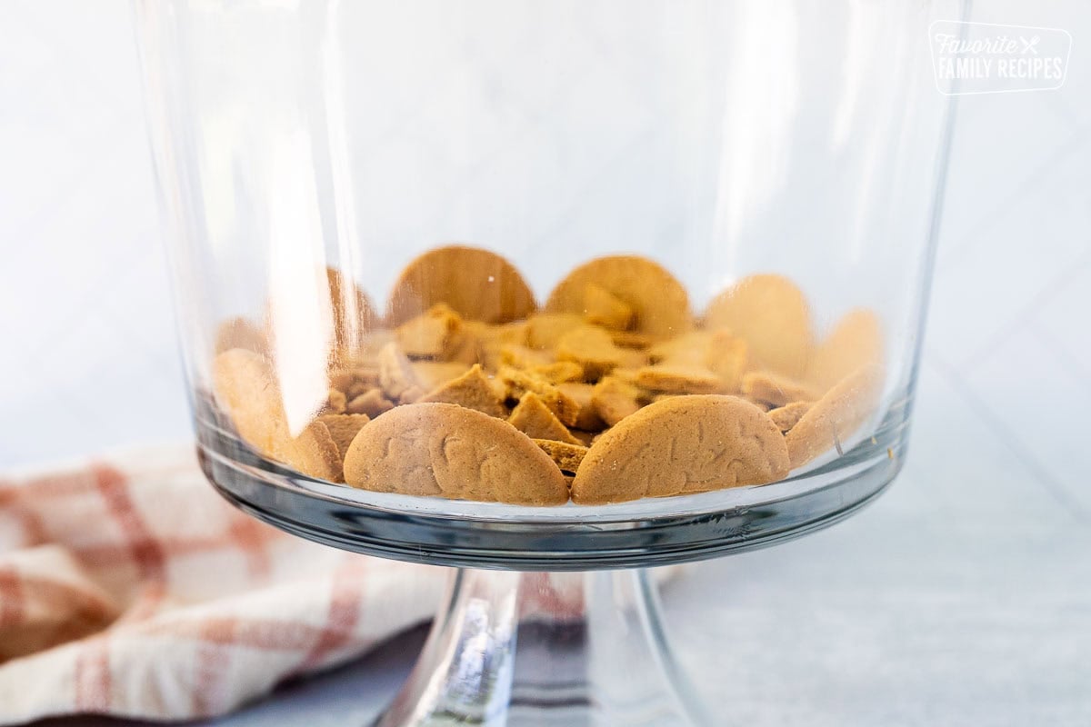 Ginger snaps lined up on the edge of the trifle dish with cut pieces in the middle.