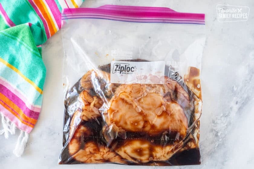Ziploc bag with raw chicken breasts and teriyaki marinade.