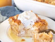 Cut corner of a slice of Apple Bread Pudding with caramel sauce and whipped cream.