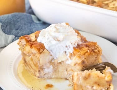 Cut corner of a slice of Apple Bread Pudding with caramel sauce and whipped cream.