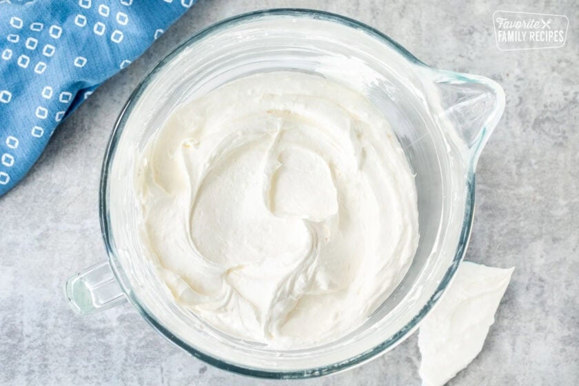 Glass mixing bowl with cool whip and cream cheese mixture.