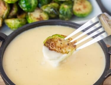Dipping Brussels Sprouts into sauce with a fork.