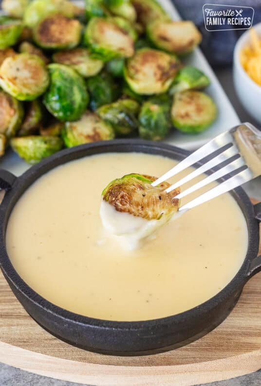 Dipping Brussels Sprouts into sauce with a fork.