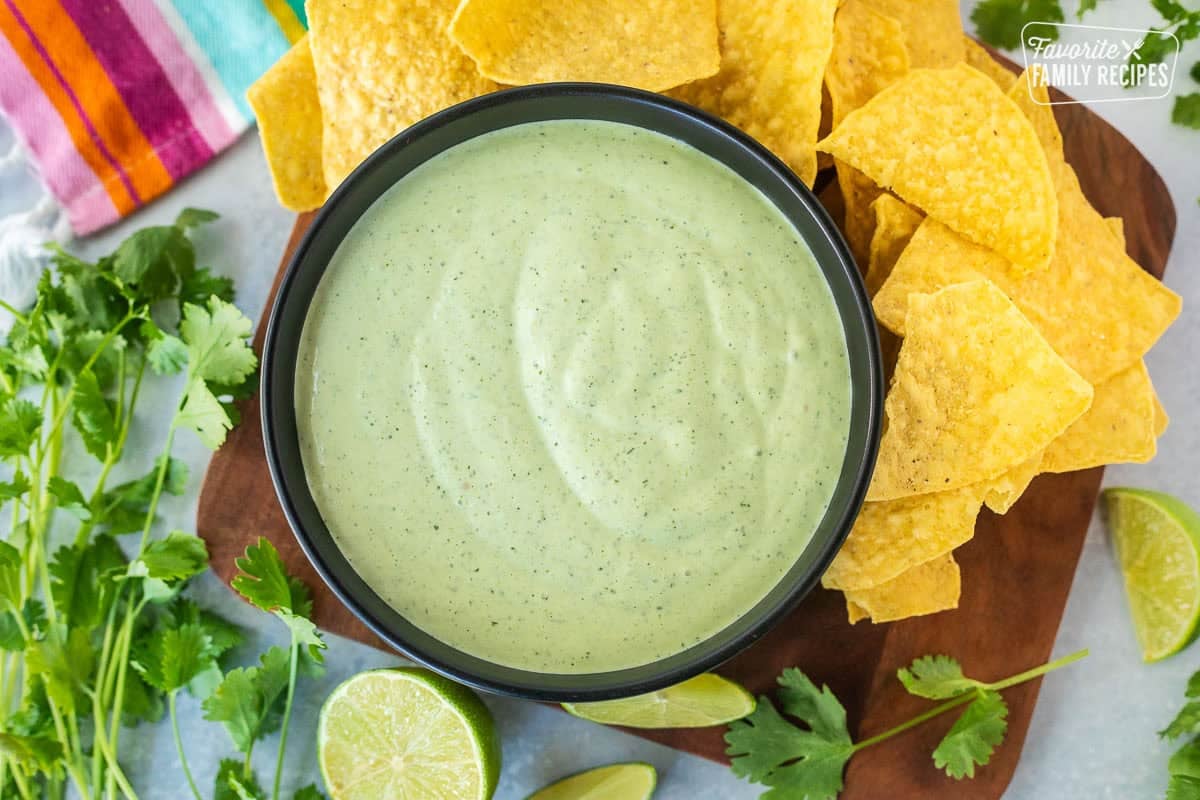 Bowl of creamy cilantro lime sauce next to tortilla chips.