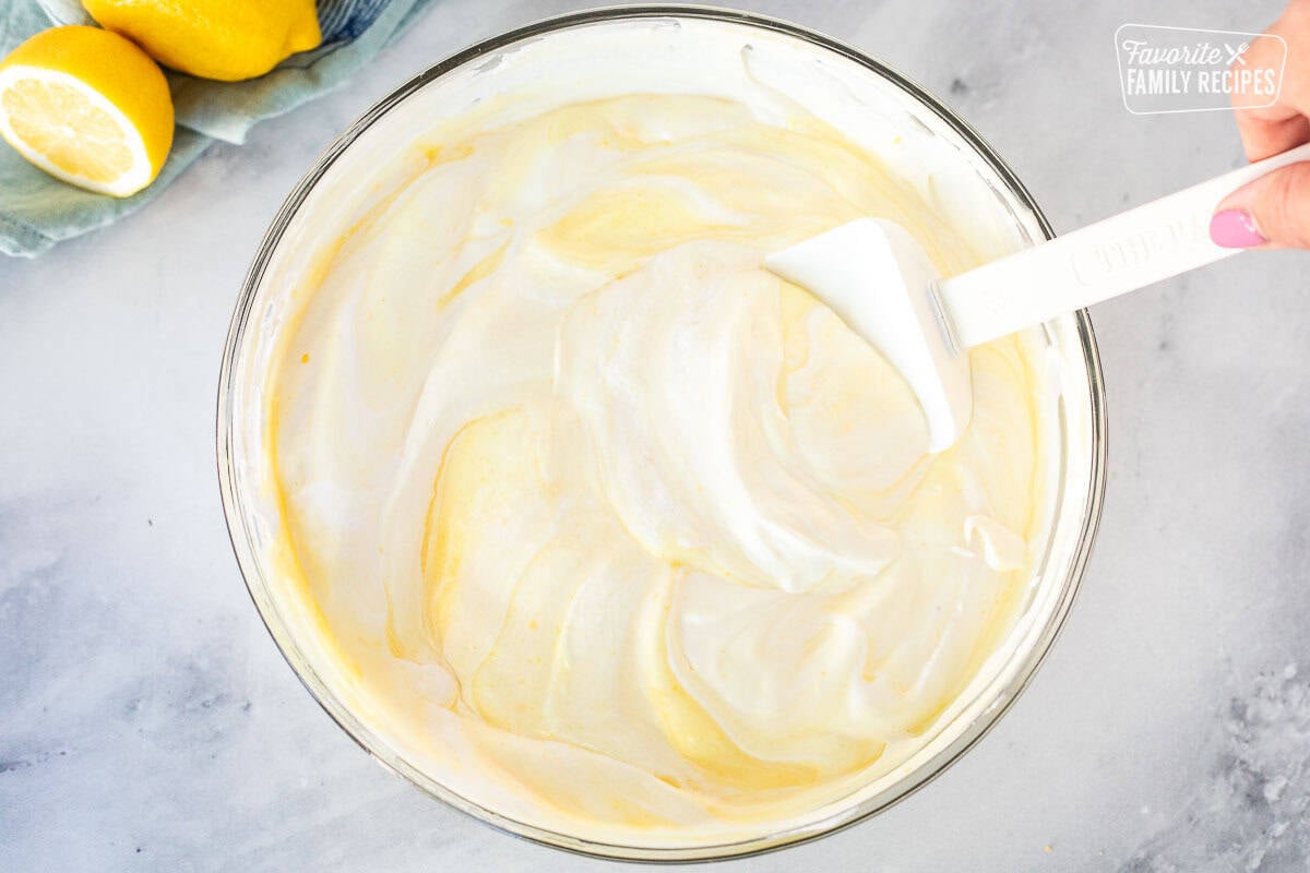 Glass mixing bowl with lemon pudding mix combining with Cool Whip.