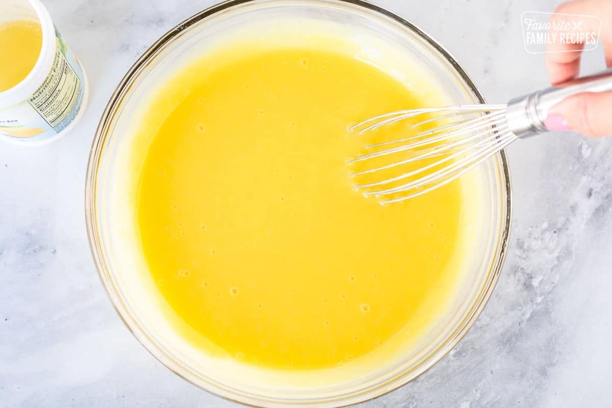 Whisking lemon juice and pudding mixture in a large glass bowl.