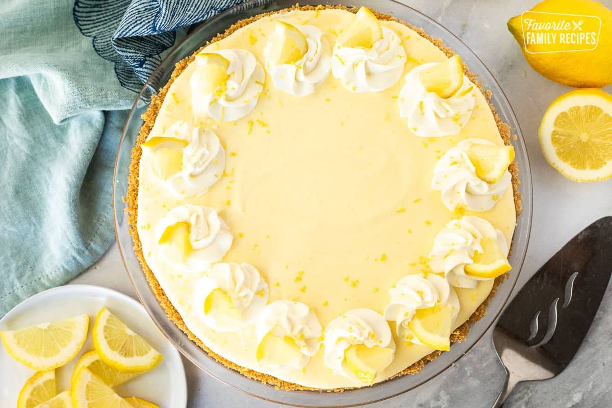 Decorated Creamy Lemon Pie decorated with whipped cream, lemon slices and lemon zest on top.