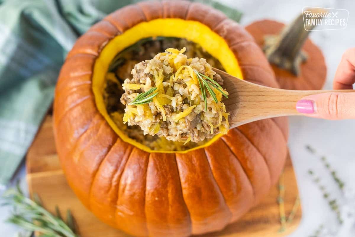 Dinner in a Pumpkin is a hearty casserole cooked right inside a pumpkin! Perfect for serving on Halloween night before the kids go trick-or-treating. Ground beef and rice dinner in a pumpkin being served from a pumpkin shell.