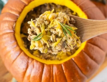 Wooden spoon with Dinner in a Pumpkin garnished with rosemary.