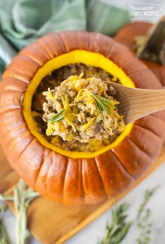 Wooden spoon with Dinner in a Pumpkin garnished with rosemary.