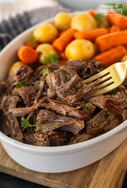 Instant pot chuck roast shredded in dish and piece on fork.