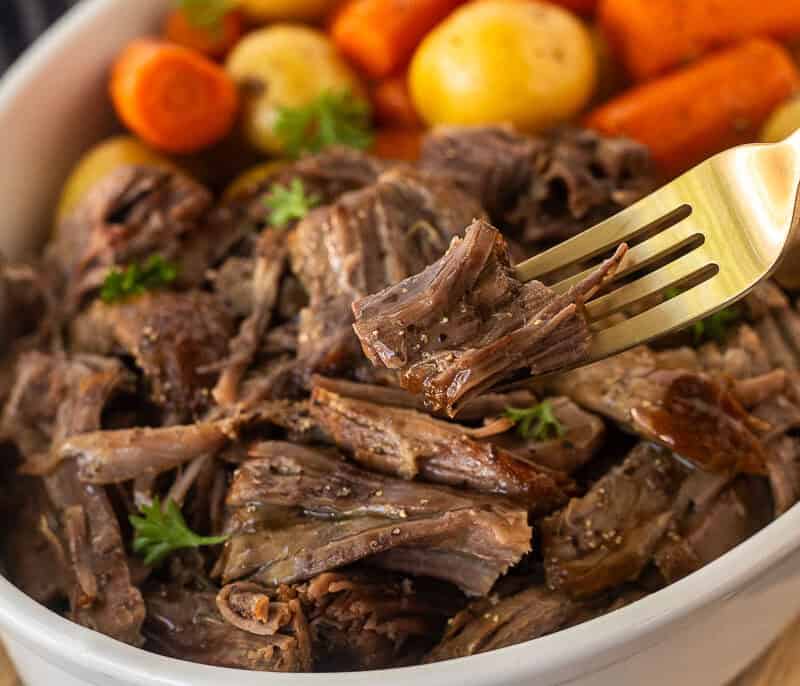 Instant pot chuck roast shredded in dish and piece on fork.