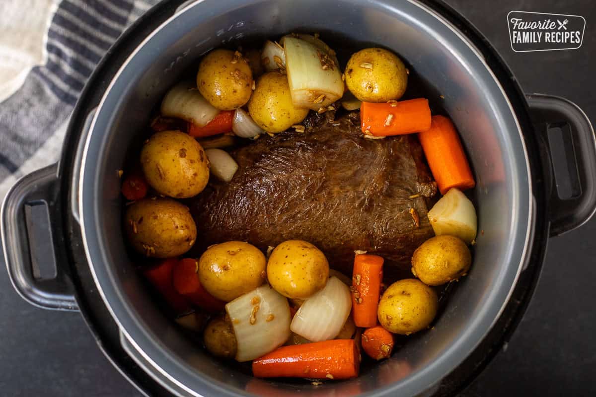 Instant pot with chuck roast and vegetables and broth.